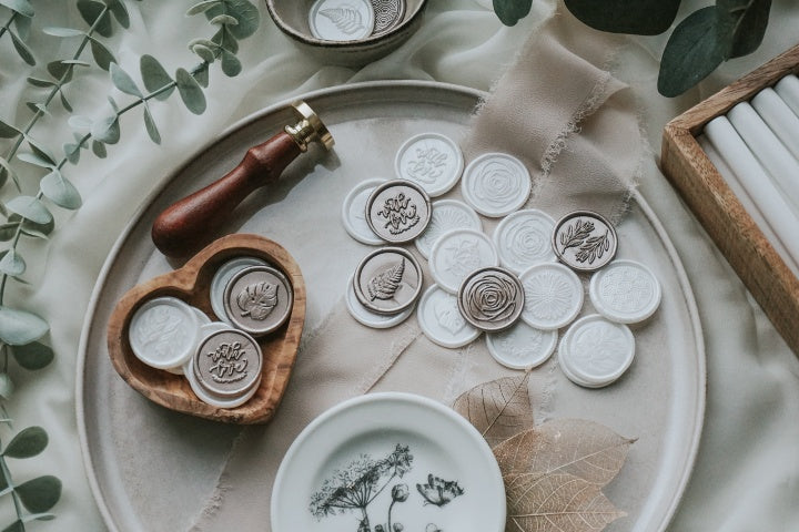 multiple_designs-wax_seals_in_bowl_and_laid_out-Dove_white-Antique_gold-floral-botanical-background - Made of Honour Co.16184552193b4706ec-0