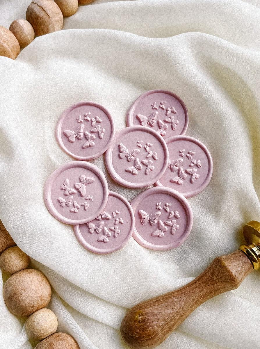 Butterfly wax seals in Ballet with cloth and wax stamp in the background.