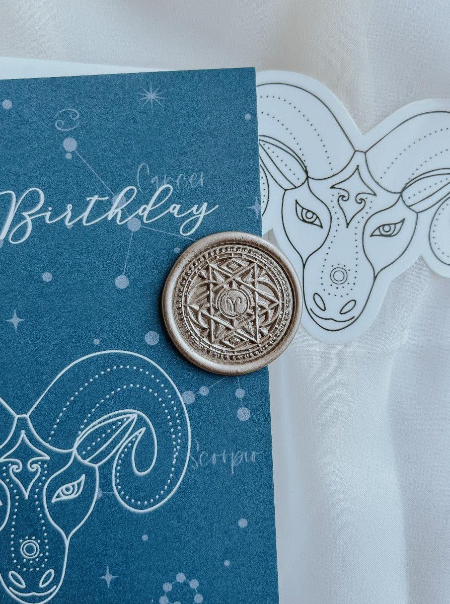 Aries wax seal in Antique gold colour with aquamarine aries card and matching sticker in the background.