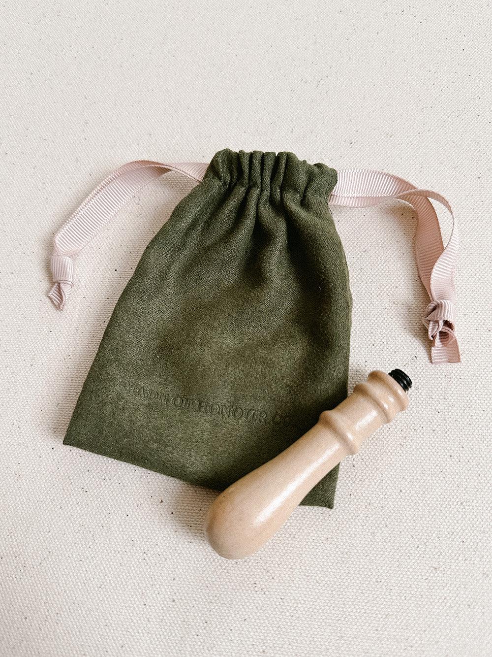 green suede bag with made of honour co logo embossed