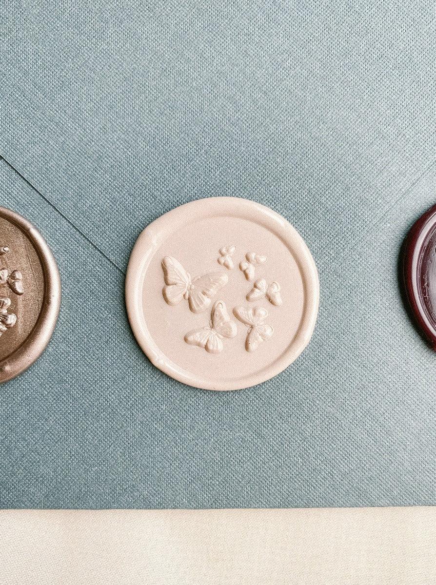 Butterfly wax seal in Ballet colour with envelope in the background.