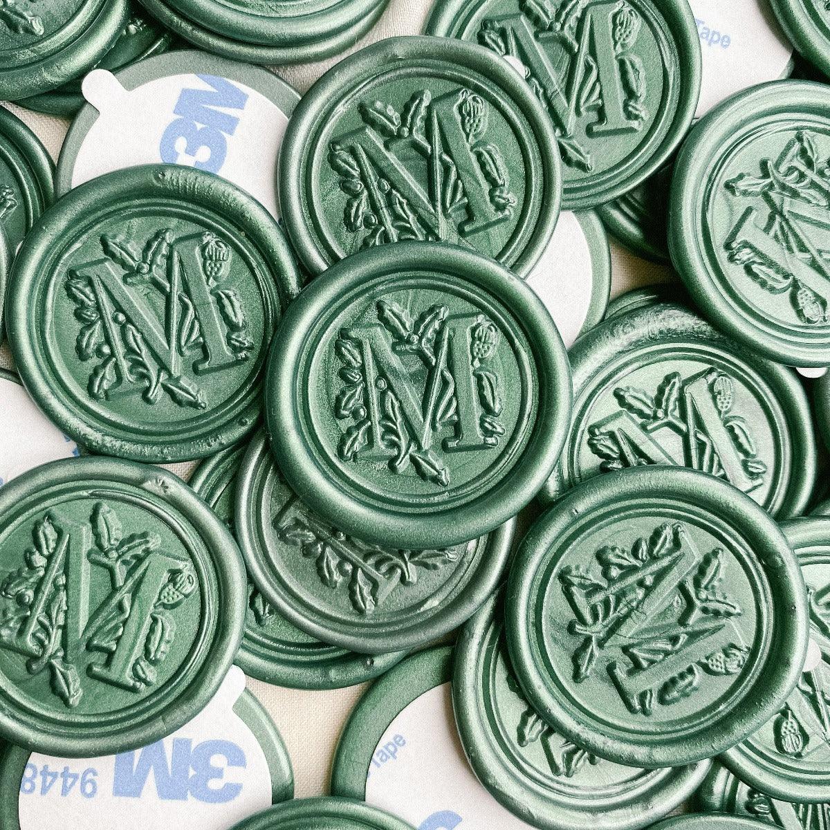 Letter M wax seals in Metallic pine colour with wax seal adhesives attached.