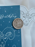 Aries wax seal in Antique gold colour with aquamarine aries card and matching sticker in the background.